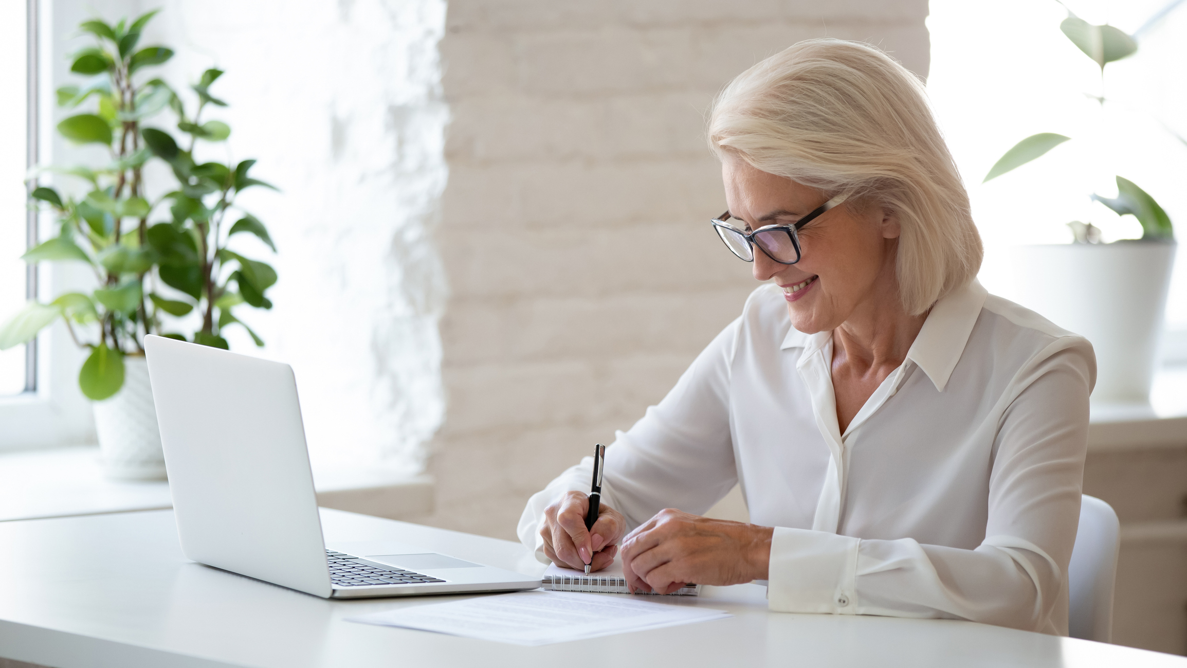 Mature businesswoman sitting at desk writing info thoughts on notepad, personal development get knowledge using internet sites, on-line research, teacher prepares for lesson, create to-do list concept